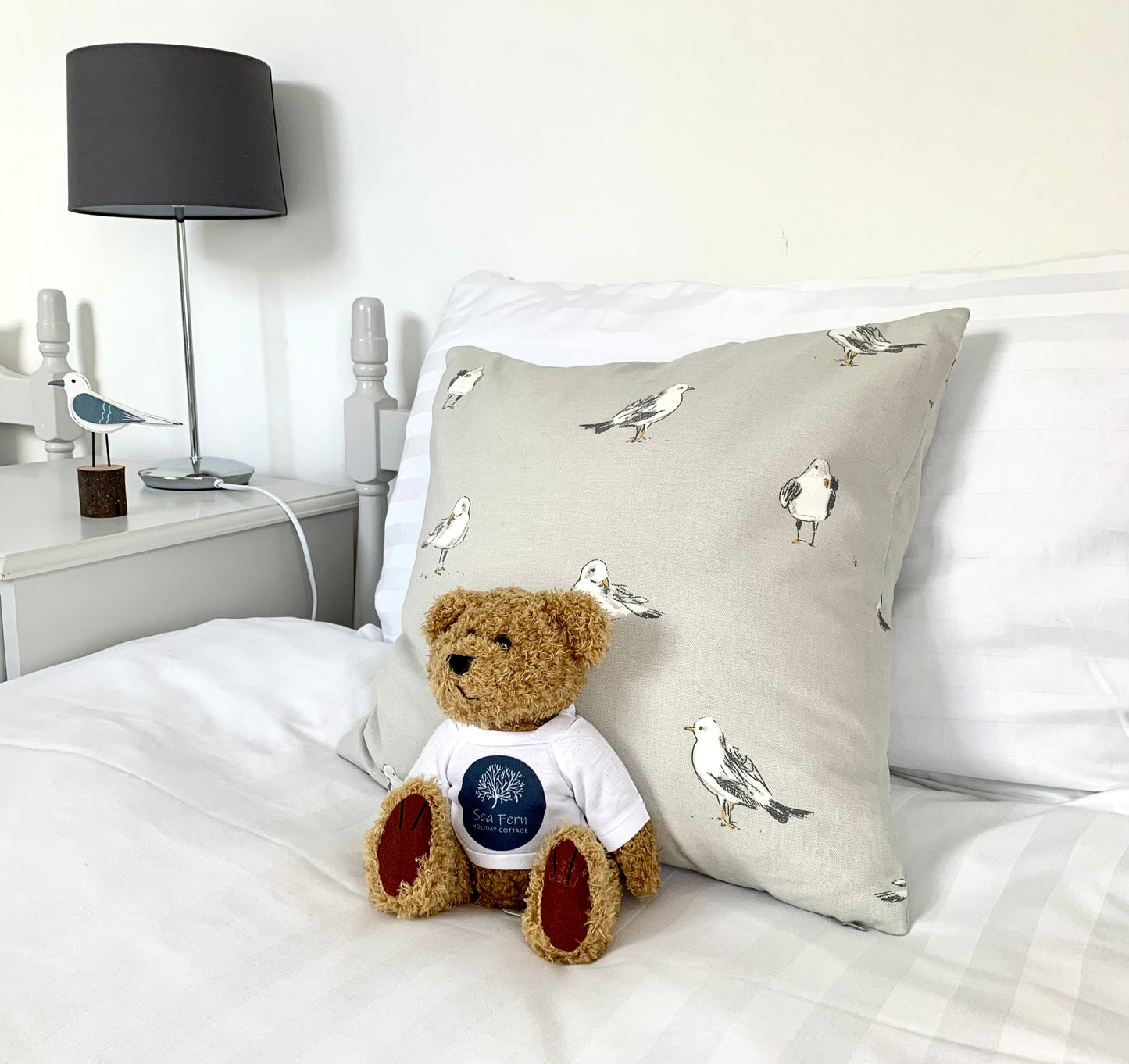 Branded teddy bear on a child's bed in a holiday home environment.