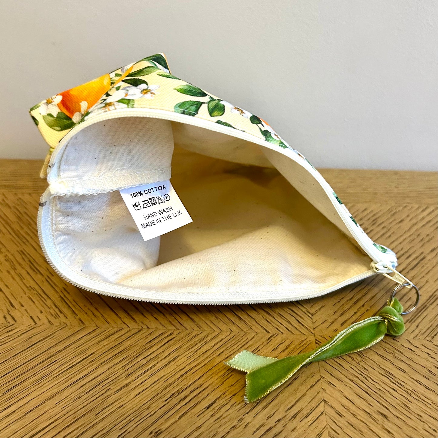 toiletry bag in orange blossom print showing label with hand washing instructions.