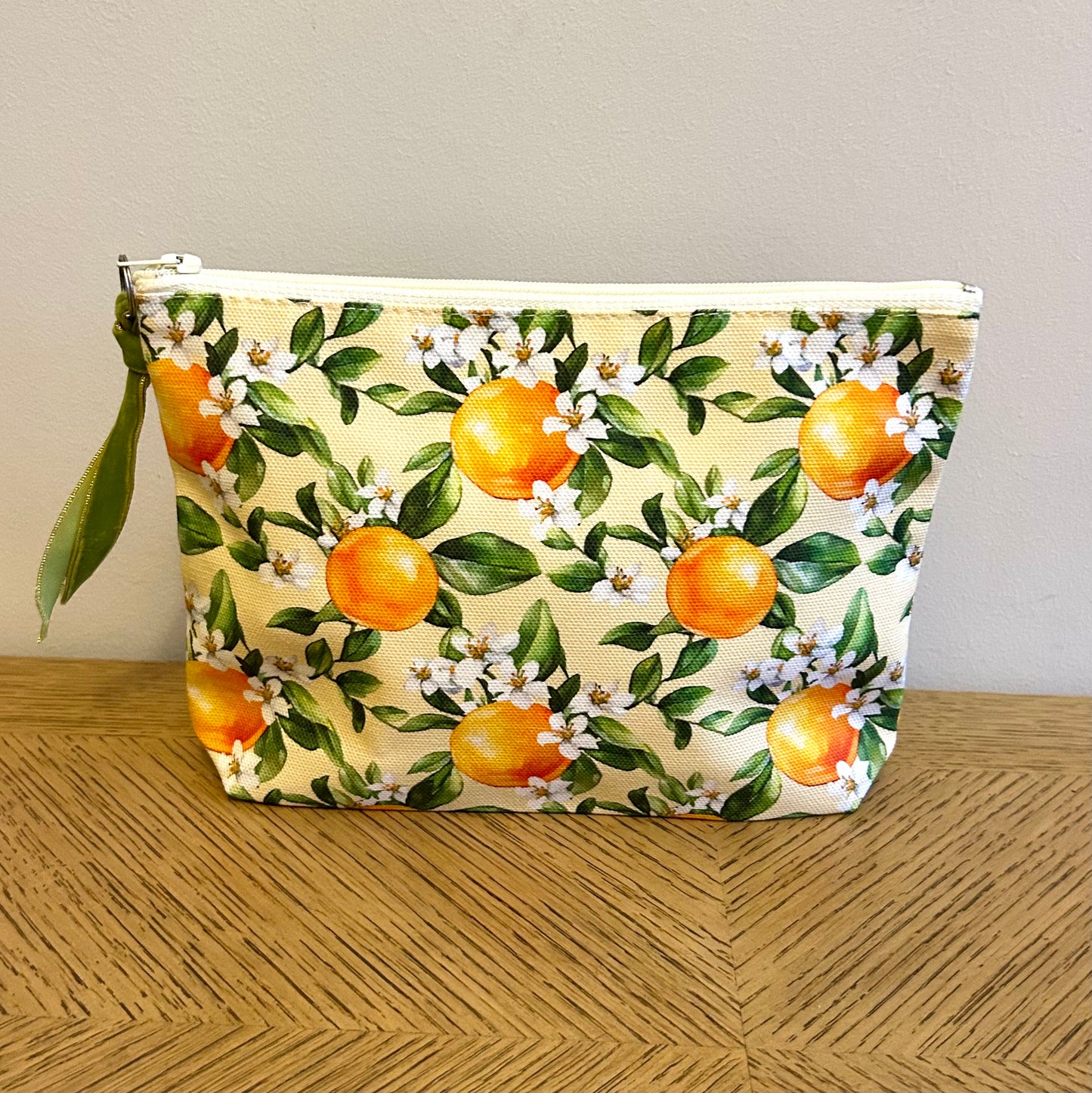 toiletry bag in an orange blossom print with a velvet ribbon zip pull.