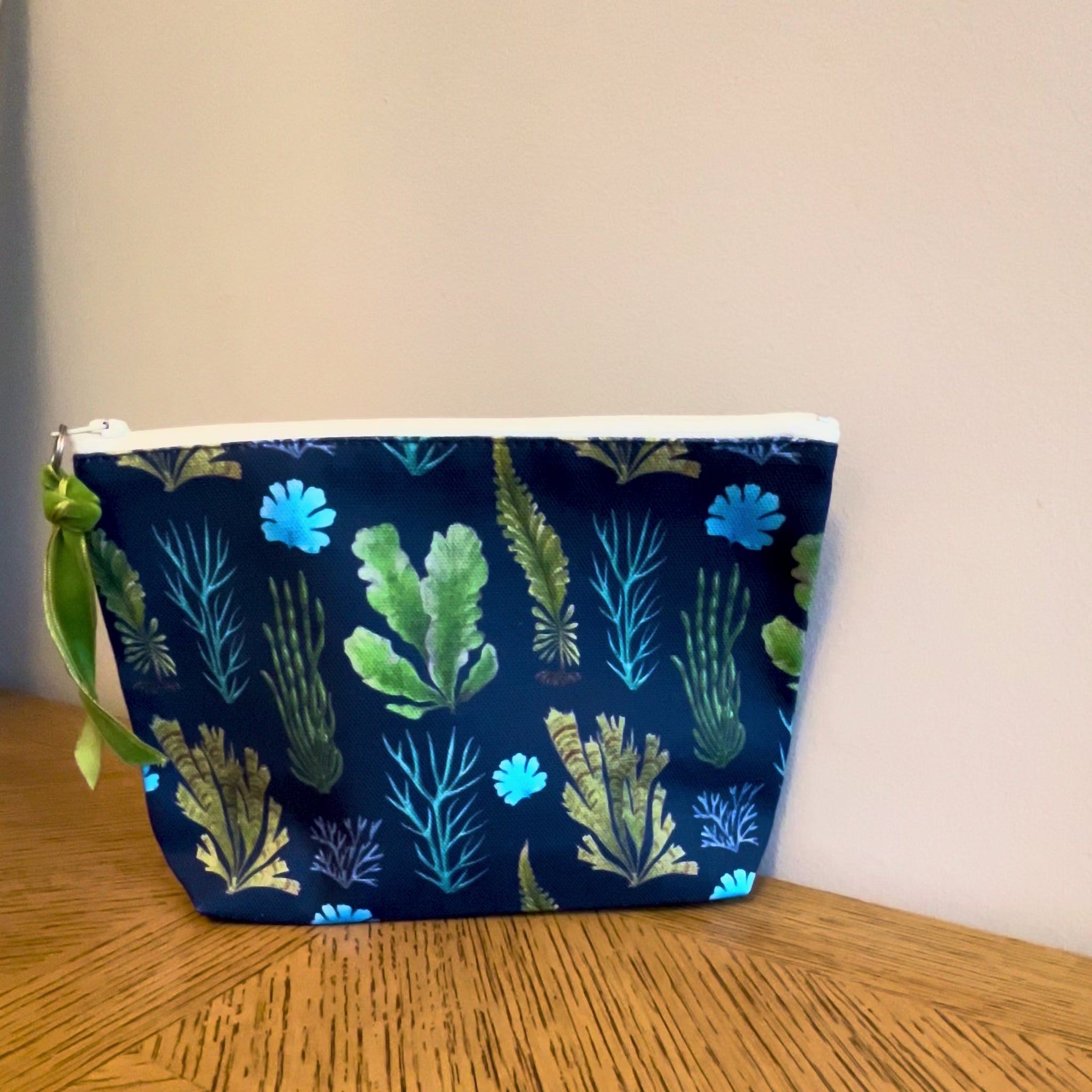 Blue cosmetic toiletry bag with a British seaweed print lined with a zip and gusset. Labelled Made in the UK