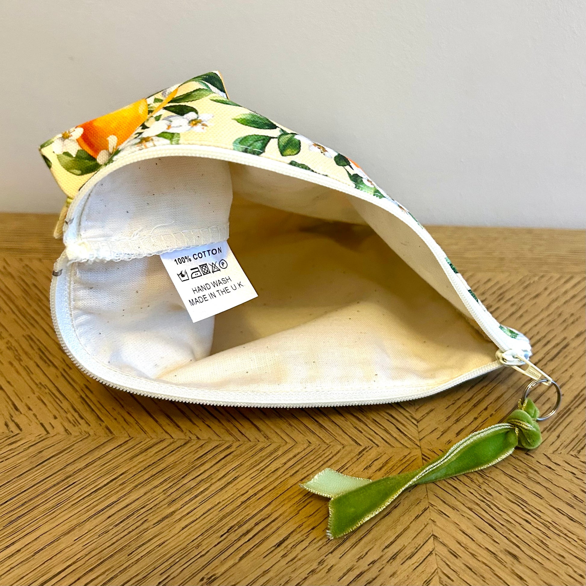 toiletry bag in orange blossom print showing label with hand washing instructions.