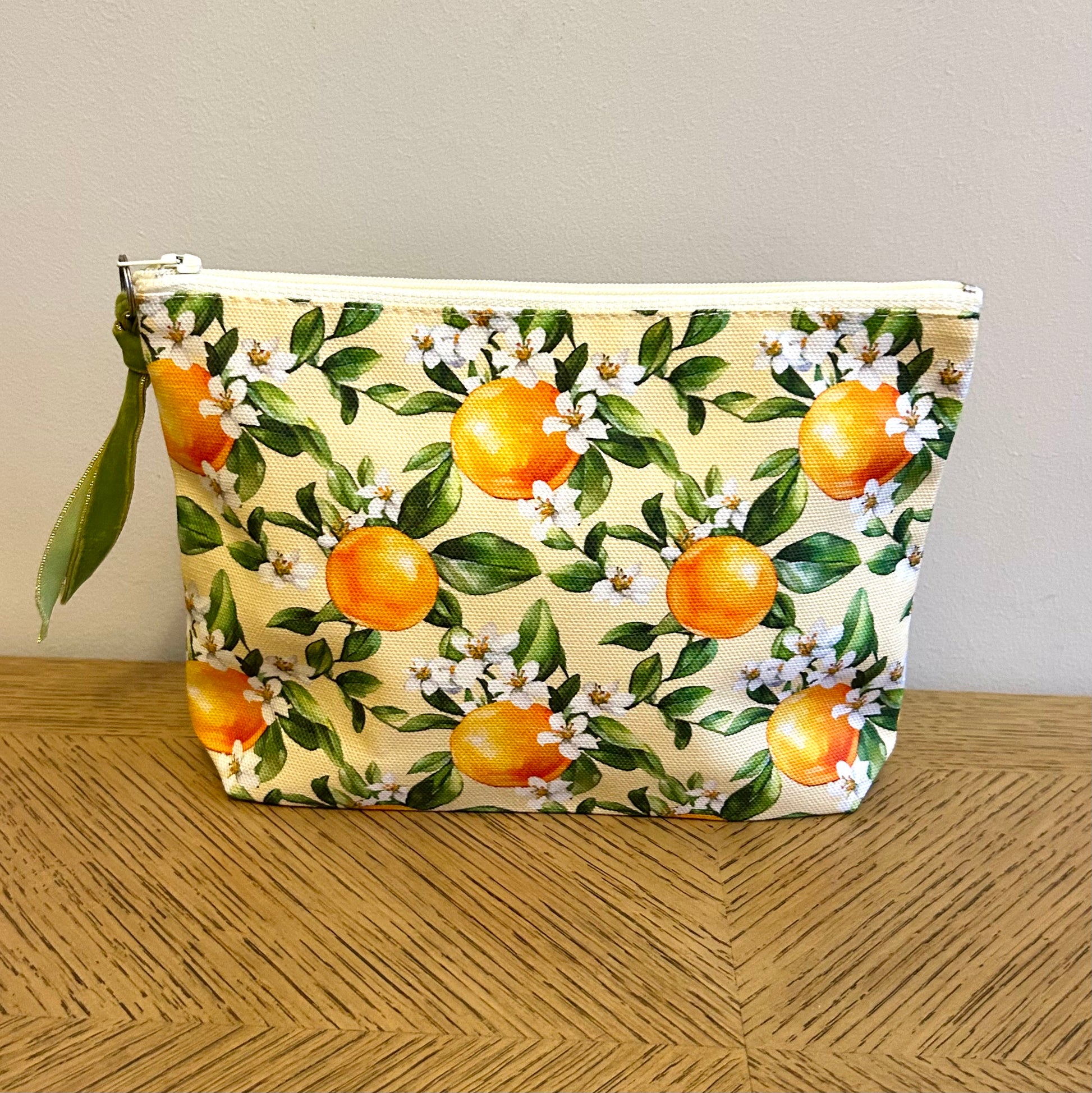 toiletry bag in an orange blossom print with a velvet ribbon zip pull.